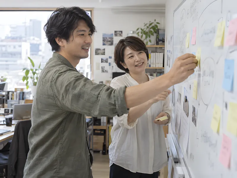 ホワイトボードの前で議論する2人